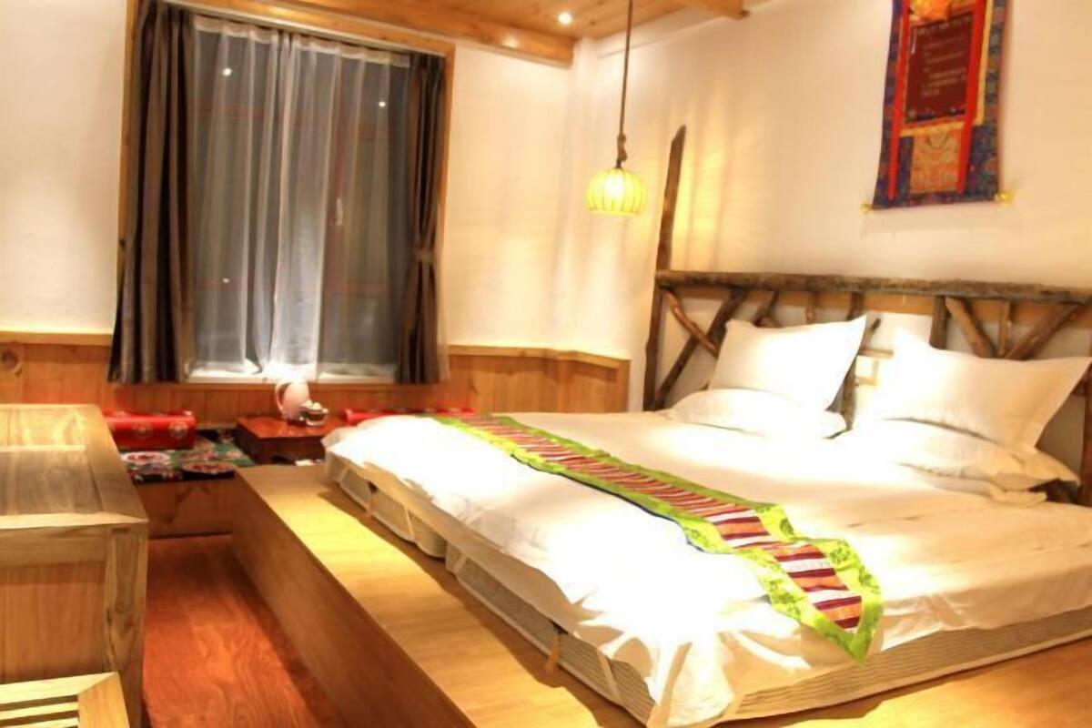 A bedroom with a wooden headboard, a bed with white linens, a bedside table, and a window with curtains.