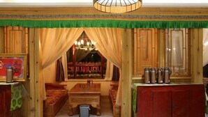 A traditional room with wooden walls, a green curtain, a wooden bench, a table, and a cabinet with metal containers.