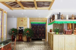 Una habitación con suelo de espiga, techo de madera, cortina verde y una recepción decorada con objetos ornamentales.