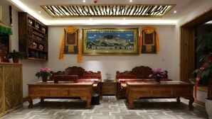 A traditional room with two wooden beds, a large painting on the wall, and a herringbone-patterned floor.