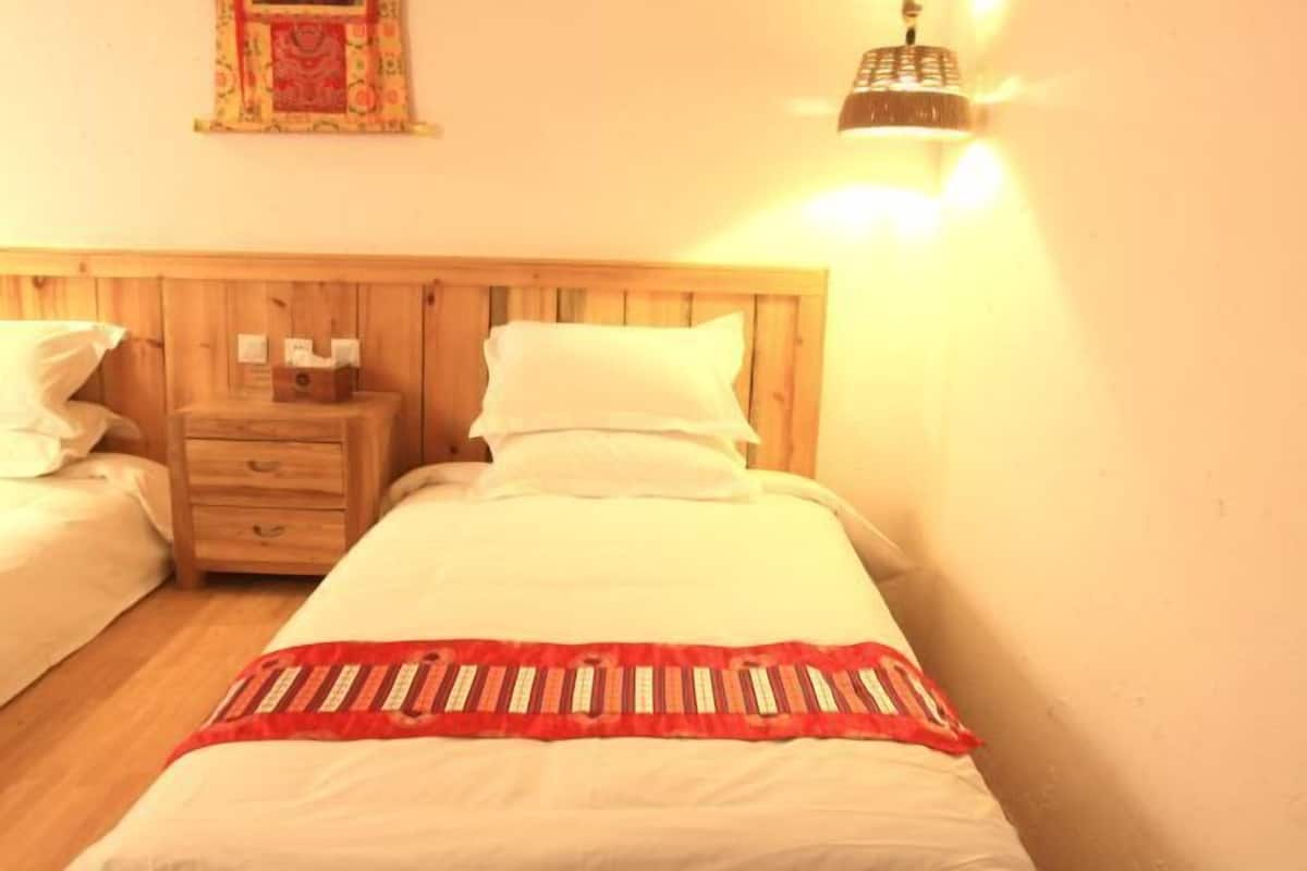 A single bed with a wooden headboard, a nightstand with a lamp, and a wall-mounted light fixture.
