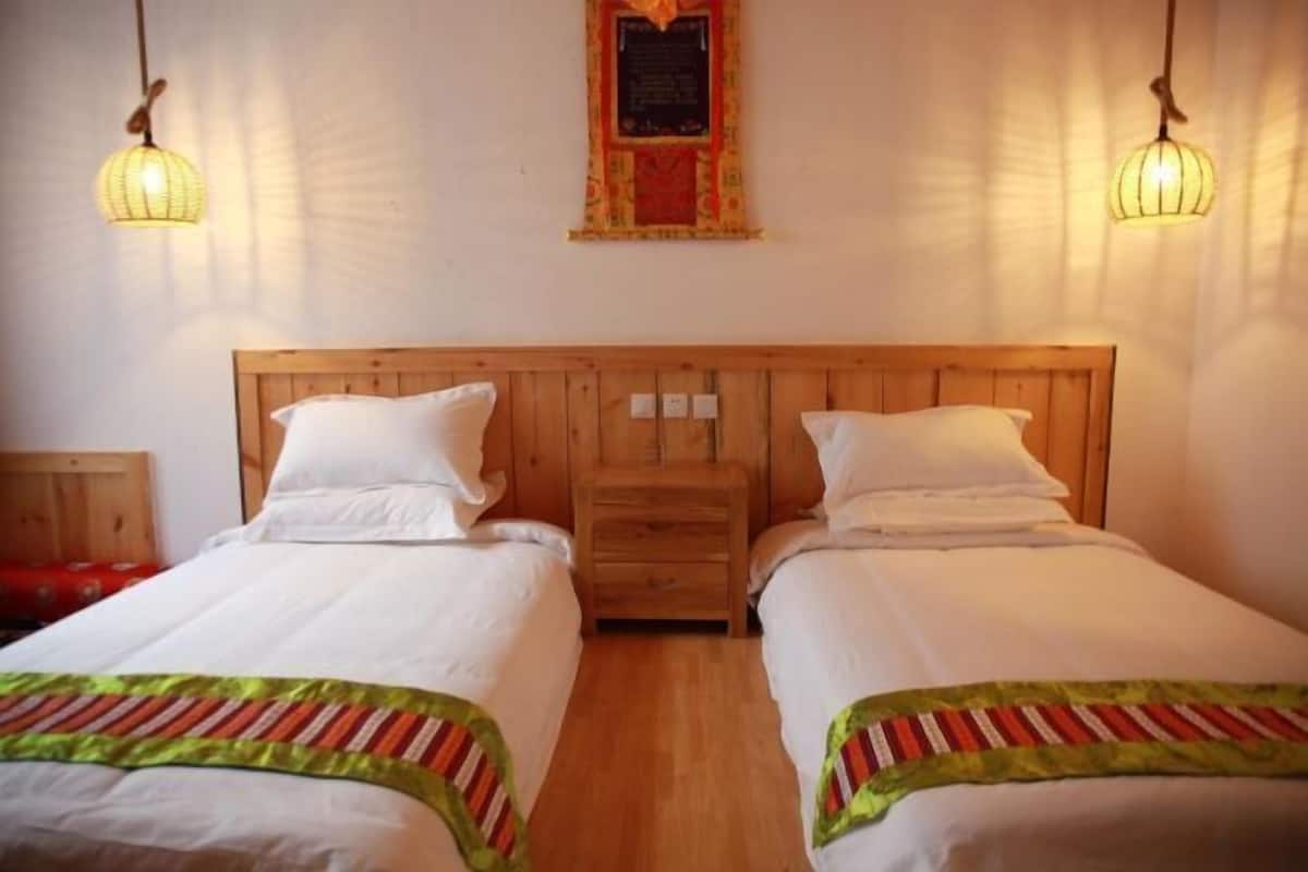 A double room with two beds, wooden headboard, bedside tables, and hanging lamps.
