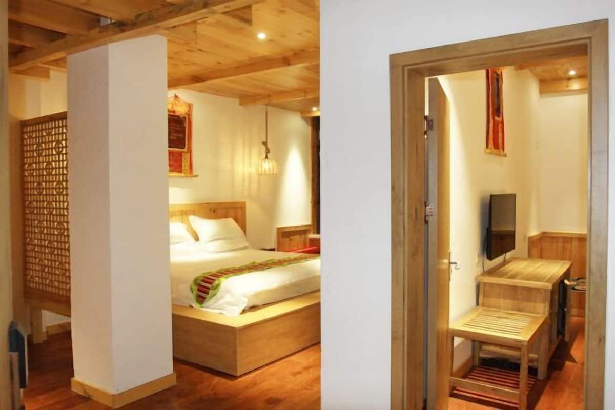 A bedroom with a wooden bed, a bedside table, a TV, and a wooden cabinet.