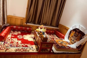 A traditional room with a red patterned carpet, wooden furniture, and a window with curtains.