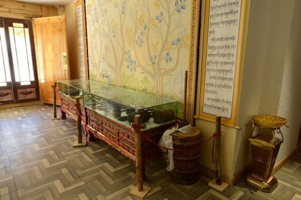 Una habitación con una vitrina de vidrio, una mesa de madera tradicional y una pared grande con un mural de un árbol.