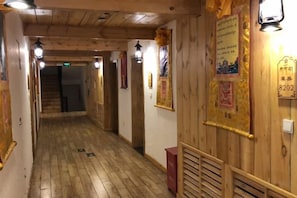 A corridor with wooden walls and a wooden floor, leading to a staircase. - Sangpei Dongzhu Inn (Xiahe)