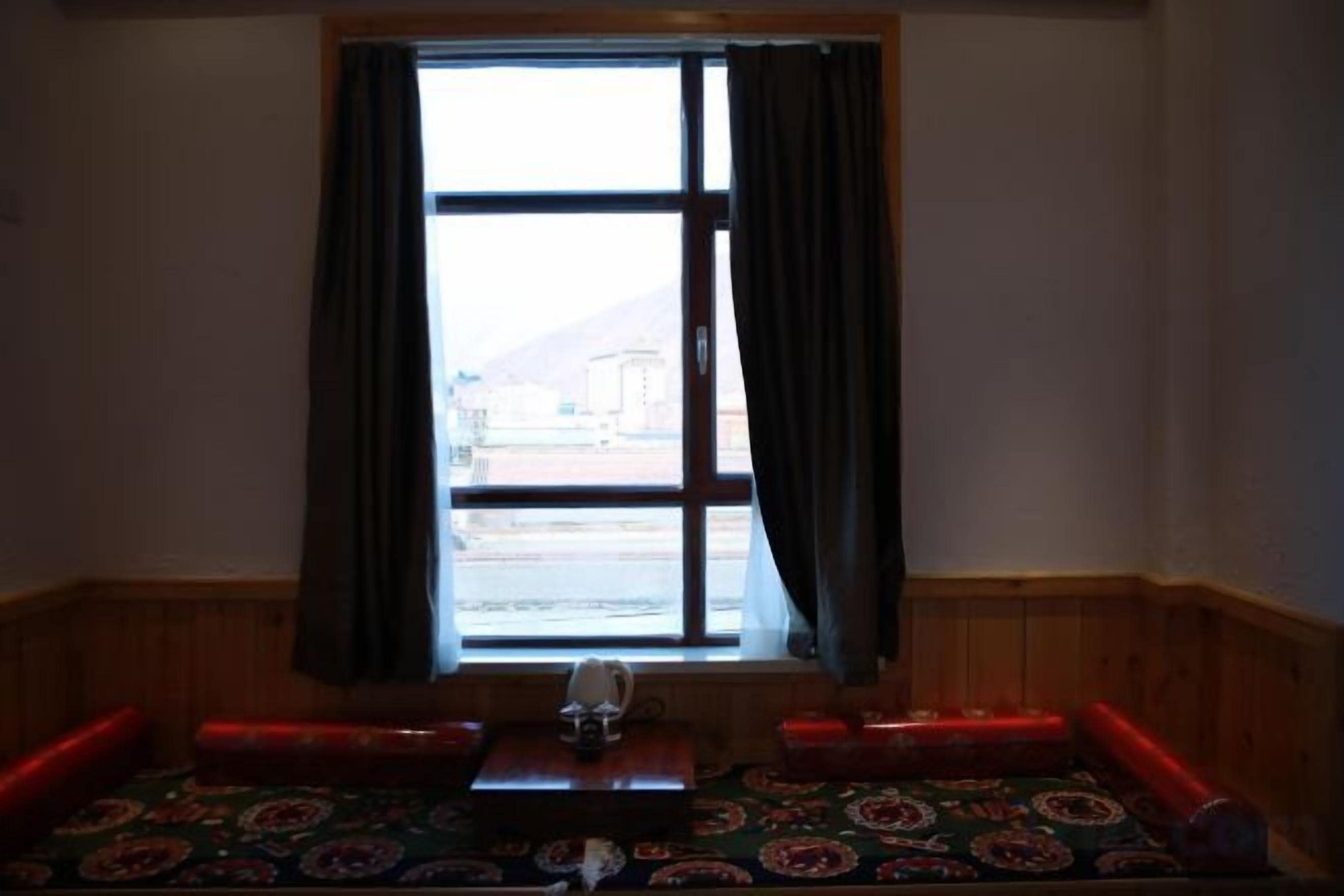 A room with a large window, a sofa, and a small table.