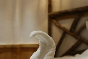 Uma toalha branca com design curvo, possivelmente um porta-toalhas, em um quarto com detalhes em madeira e uma cortina.