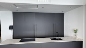 A modern kitchen with dark cabinetry, a sleek black faucet, and a marble countertop.