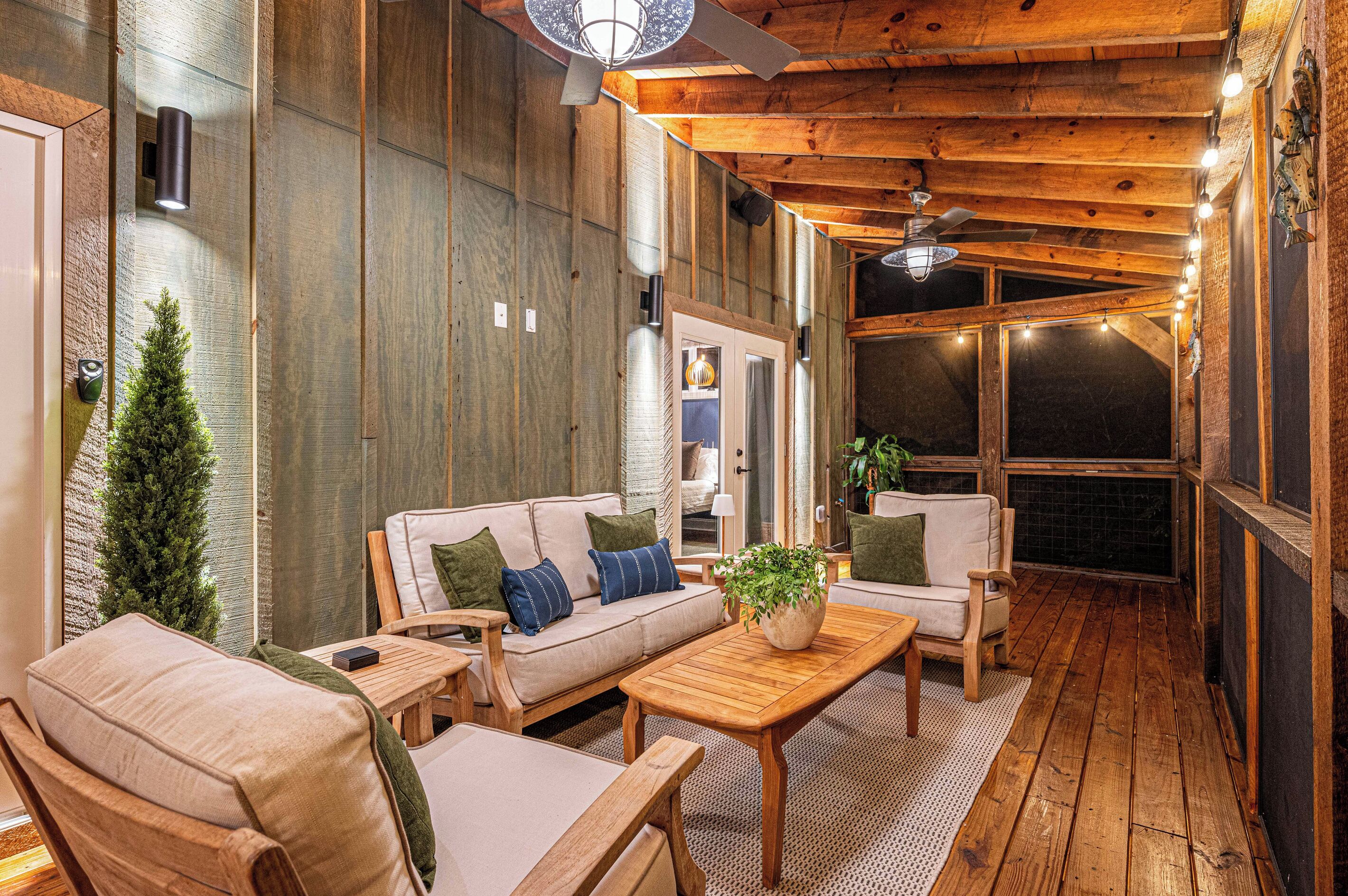 A cozy outdoor seating area with a wooden ceiling, a sofa with cushions, and a coffee table.