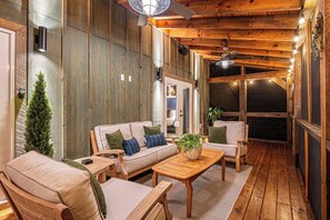 Un espace extérieur accueillant, doté d’un plafond en bois, d’un canapé avec des coussins et d’une table basse.