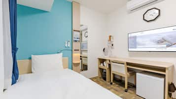 A hotel room with a bed, desk, and a small refrigerator.