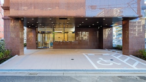Een gebouwtoegang met een hellingbaan en een parkeerplaats voor mindervaliden.