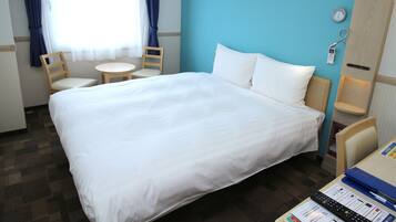 A hotel room with a large bed, two chairs, a small table, and a clock on the wall.
