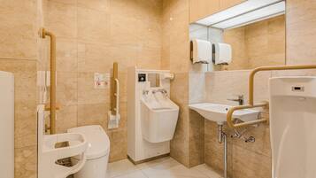 Un baño moderno con inodoro, bidé, lavamanos y barras de apoyo.