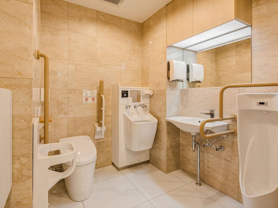 Un baño moderno con inodoro, bidé, lavamanos y barras de apoyo.