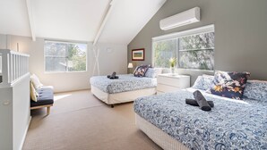 Camera da letto con due letti, ventilatore a soffitto, condizionatore d'aria e ampie finestre.