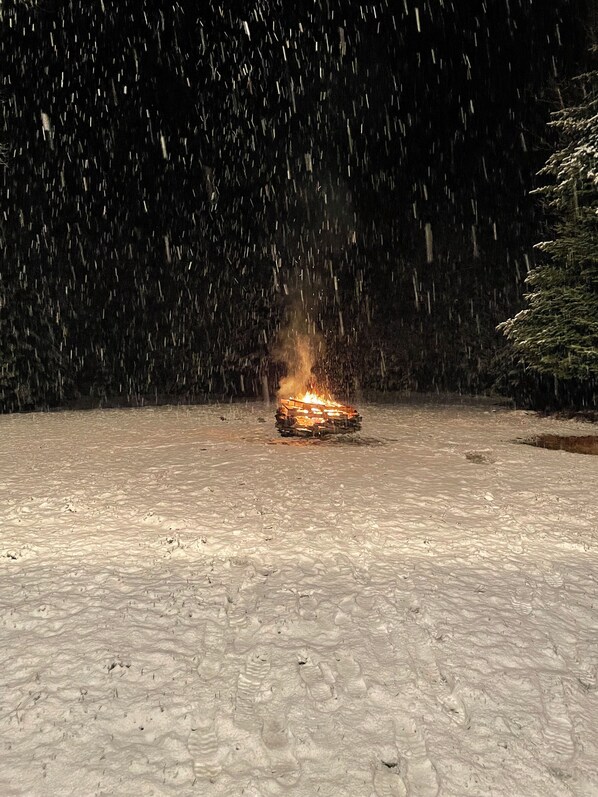 Terreno cubierto de nieve con un fuego ardiendo en el centro.