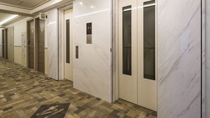 A hallway with a patterned carpet, marble walls, and doors with glass panels. - Toyoko Inn Kita-asaka-eki Nishi-guchi (Asaka)