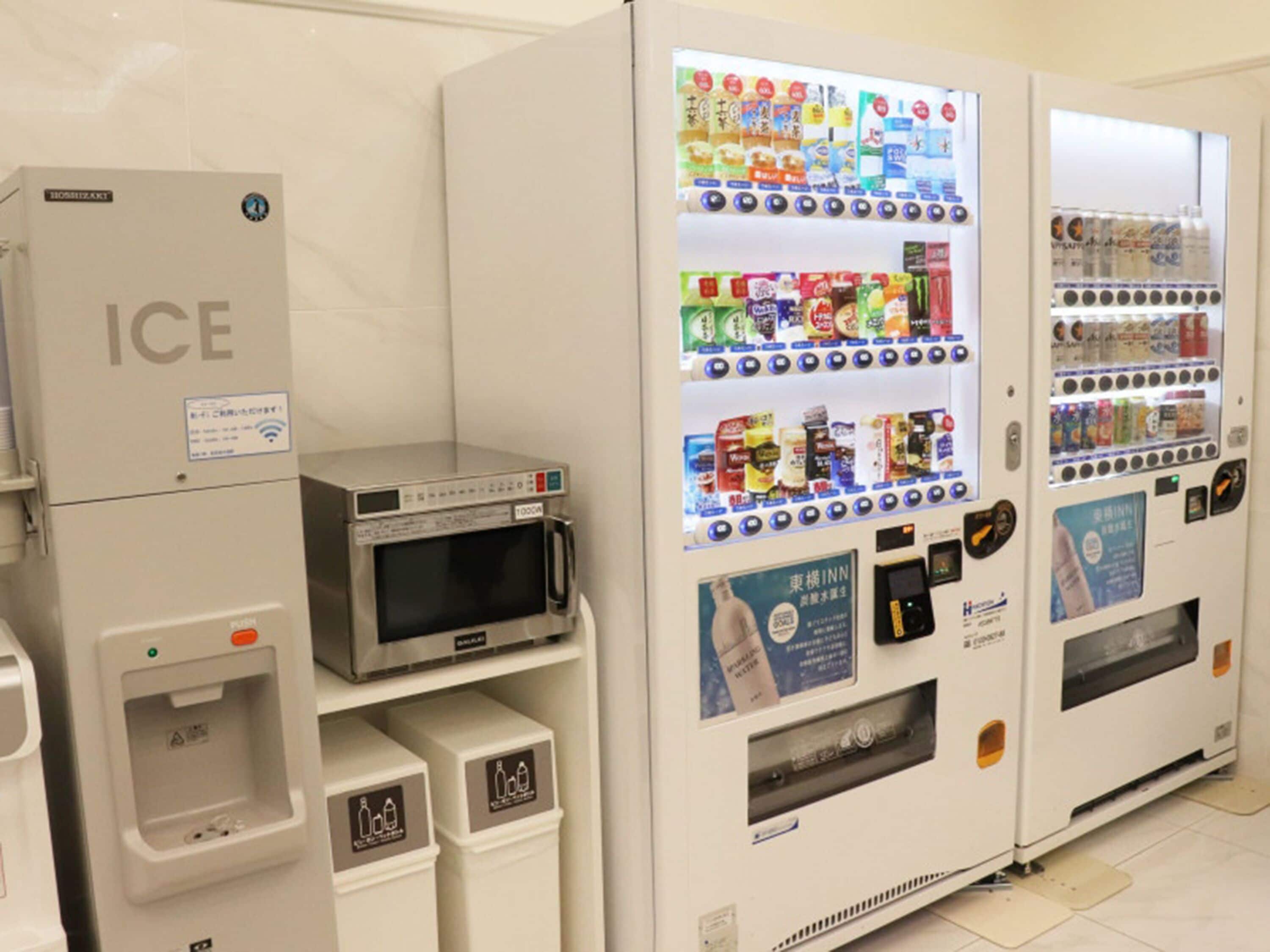 Ein Getränkeautomat mit Mikrowelle, Eiswürfelspender und einem Kühlschrank mit der Aufschrift 'ICE'.