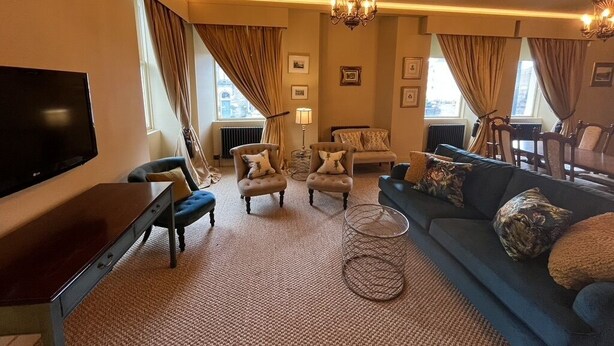 A living room with a flat-screen TV, two armchairs, a sofa, a coffee table, and a chandelier. - Luxury flat 2 mins from tram stop in the 4th coolest neighbourhood in the world! (Edinburgh)