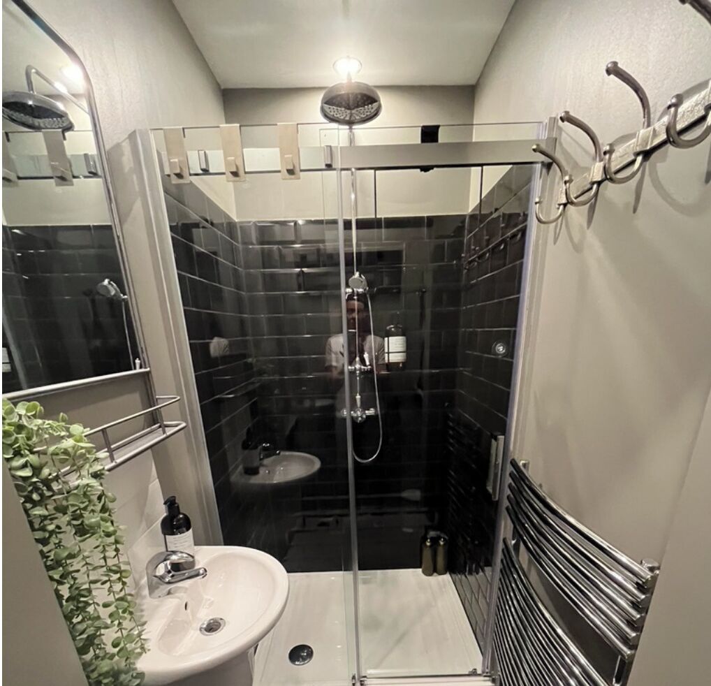A modern bathroom with a glass-enclosed shower, a white sink, and a towel rack.