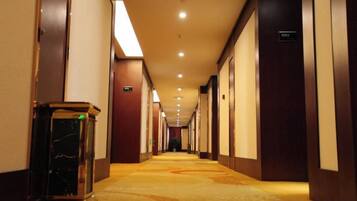 Un pasillo de hotel con piso alfombrado, puertas a la derecha y un cubo de basura a la izquierda.