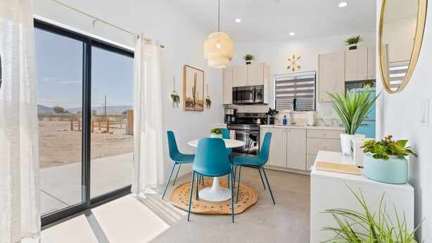 A modern kitchen with a dining area, large windows, and a view of a desert landscape. - New Listing Discount! Fire Pit~Hammocks (Joshua Tree)