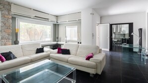 Ein modernes Wohnzimmer mit einem Ecksofa, einem Glastisch und einer Wand mit Steinverkleidung.