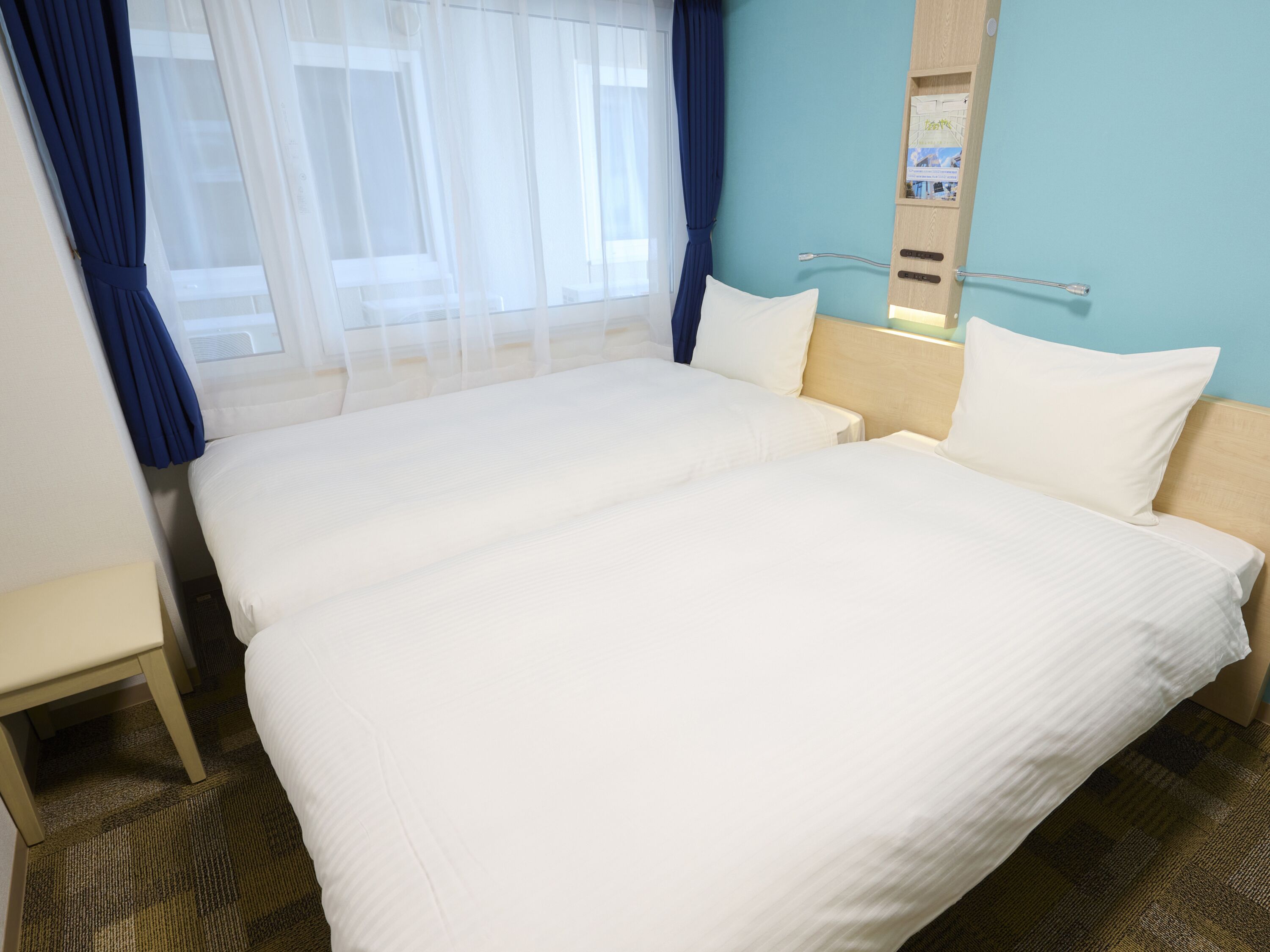 Una habitación de hotel con dos camas, una mesita y un espejo en la pared.