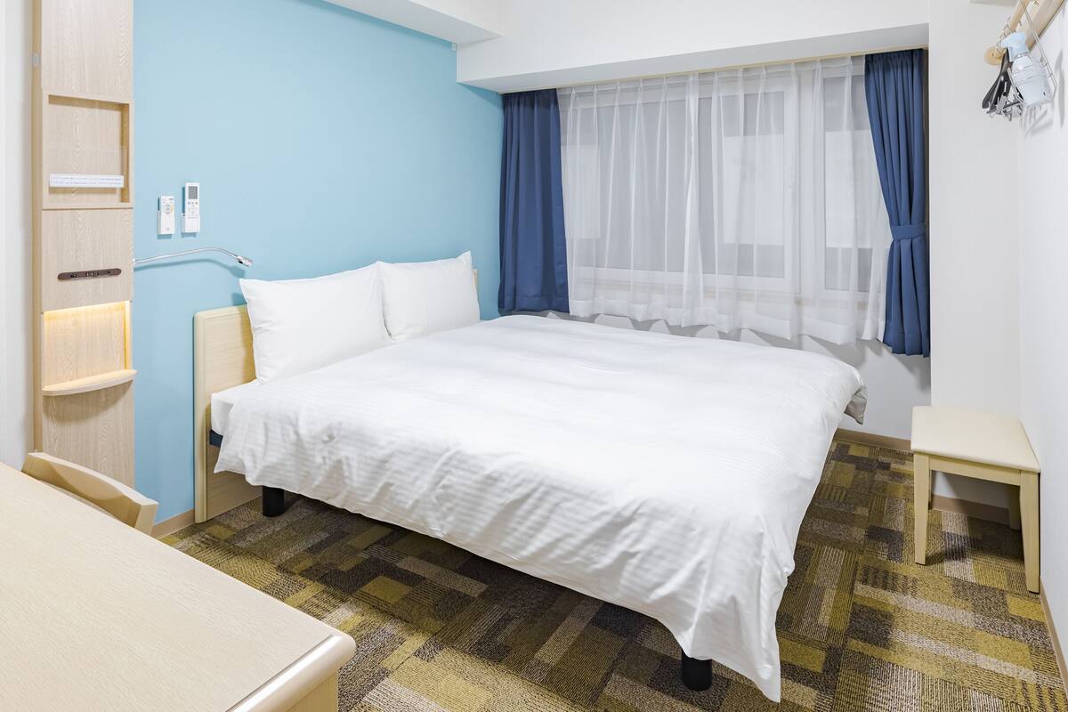 Une chambre d’hôtel avec un lit, une table de chevet et un petit bureau.