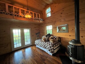 Ein Schlafzimmer in einer Blockhütte mit einem Bett, einem Teleskop, einem Kamin und großen Fenstern.