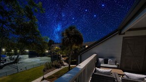Ein Balkon mit Sternenhimmel, ein Tennisplatz und ein Gebäude mit überdachter Sitzgelegenheit.