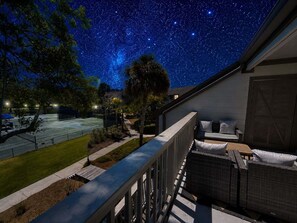 Ein Balkon mit Sternenhimmel, ein Tennisplatz und ein Gebäude mit überdachter Sitzgelegenheit.