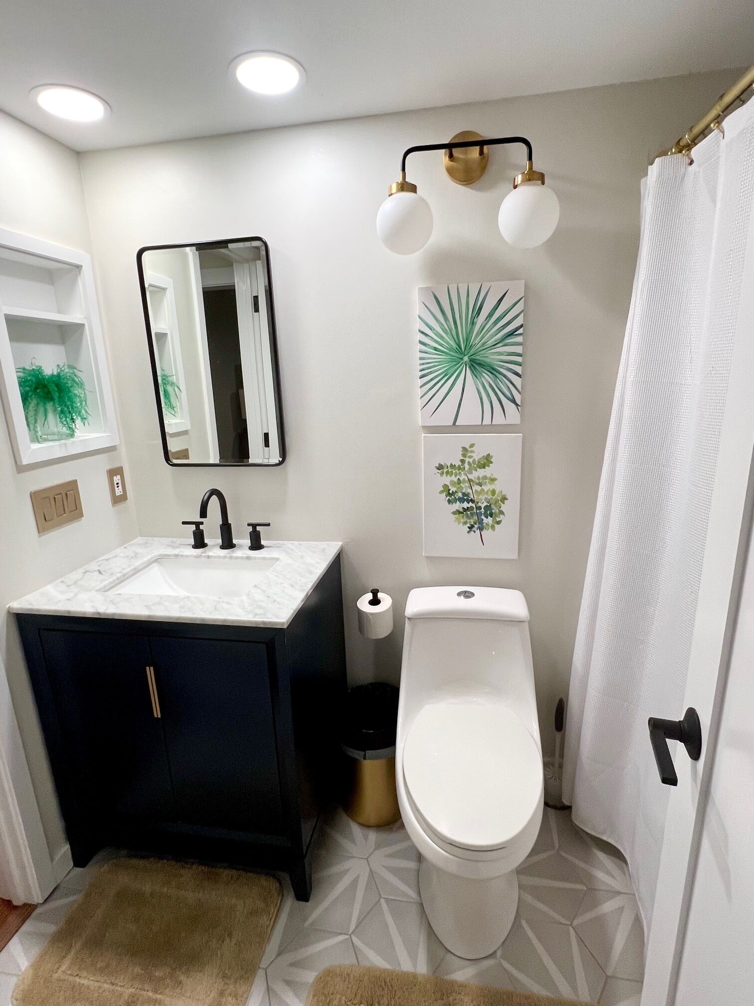 Un baño con lavamanos blanco, mueble oscuro azul, inodoro y cortina de ducha.