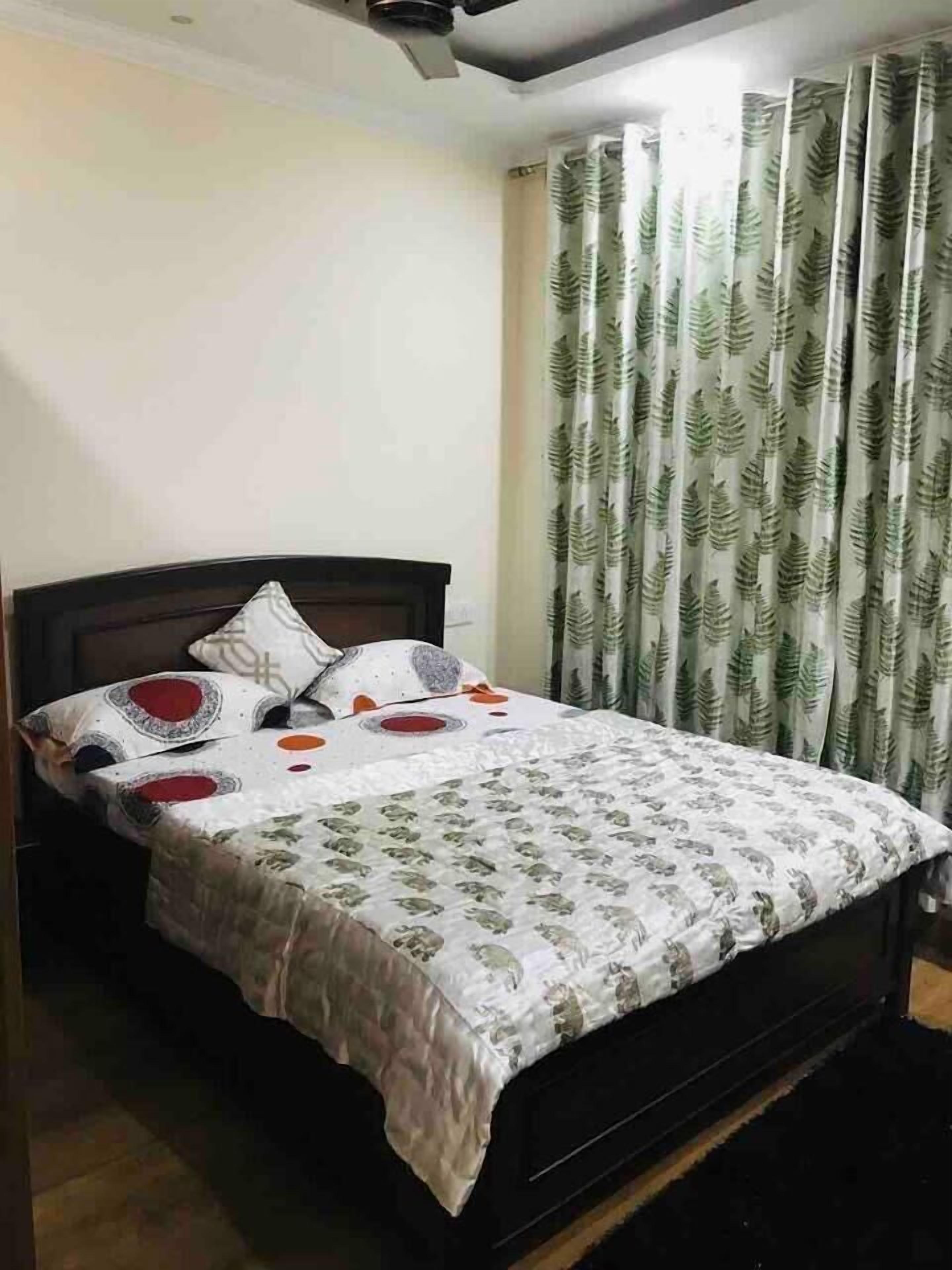 Een slaapkamer met een bed, een plafondventilator en gordijnen.