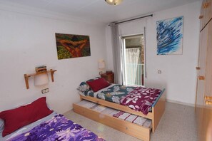 Un dormitorio pequeño y bien iluminado, con una cama individual, una mesita y una ventana.