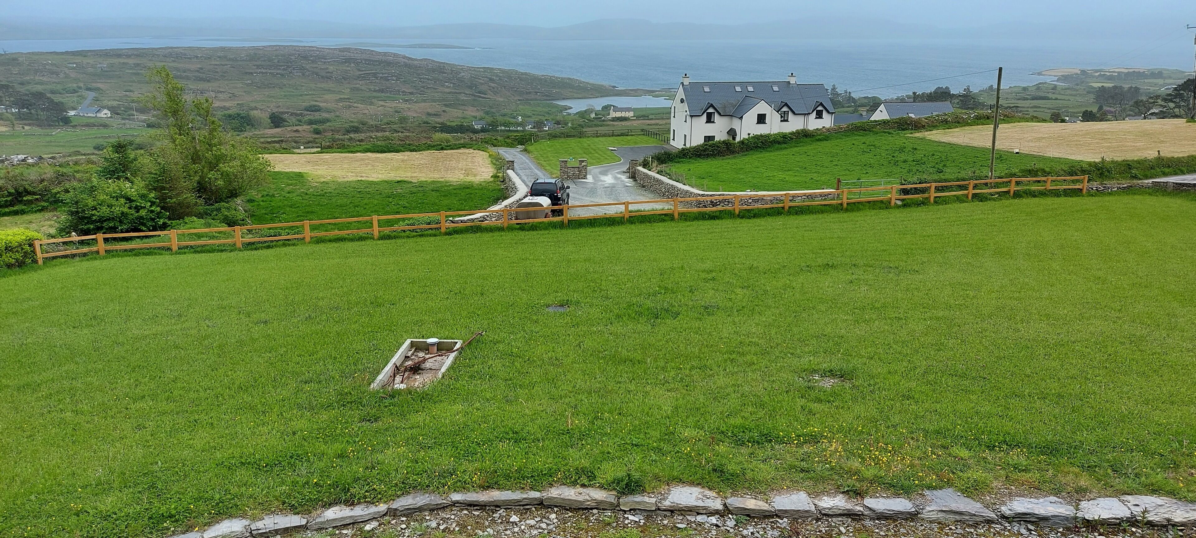 A grassy area with a stone wall and a wooden fence.
