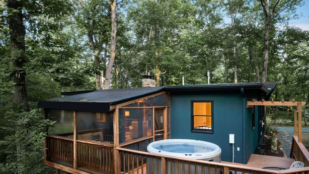Eine Holzhütte mit Whirlpool, einer Holzterrasse und einem Wintergarten.