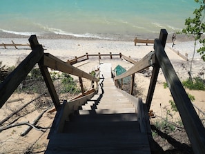 A wooden staircase leading to a beach area with a wooden fence and a green structure.