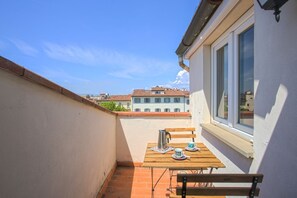 A small balcony with a wooden table set for two, a metal kettle, and a cup and saucer. - Benvenuto - Sweet Dreams in Florence (Firenze)