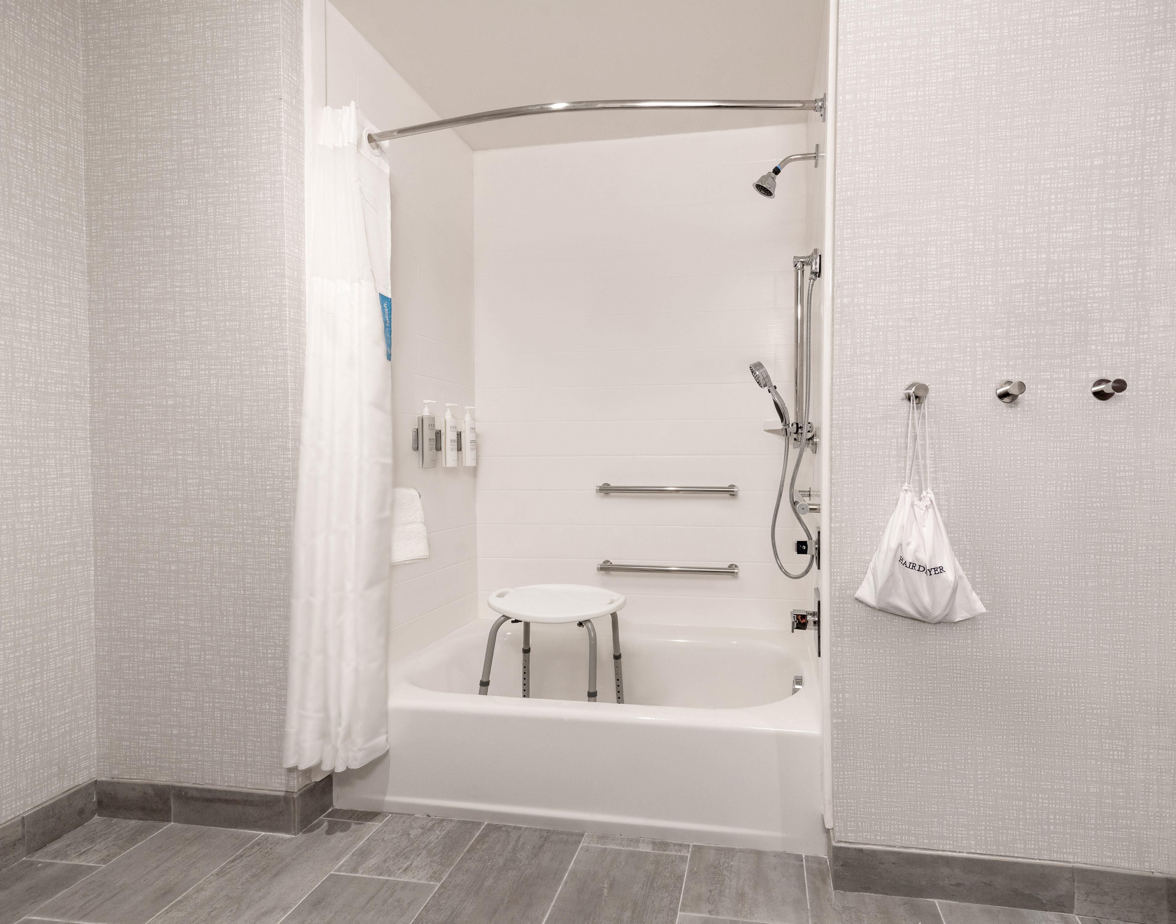 Un baño moderno con ducha a nivel, bañera y un pequeño taburete.