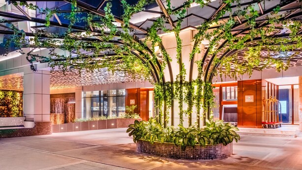 A modern hotel lobby with a central planter, glass walls, and a ceiling with a geometric pattern. - Hilton Kinshasa (Kinshasa)