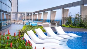 A rooftop pool area with lounge chairs and a view of the city skyline. - Hilton Kinshasa (Kinshasa)