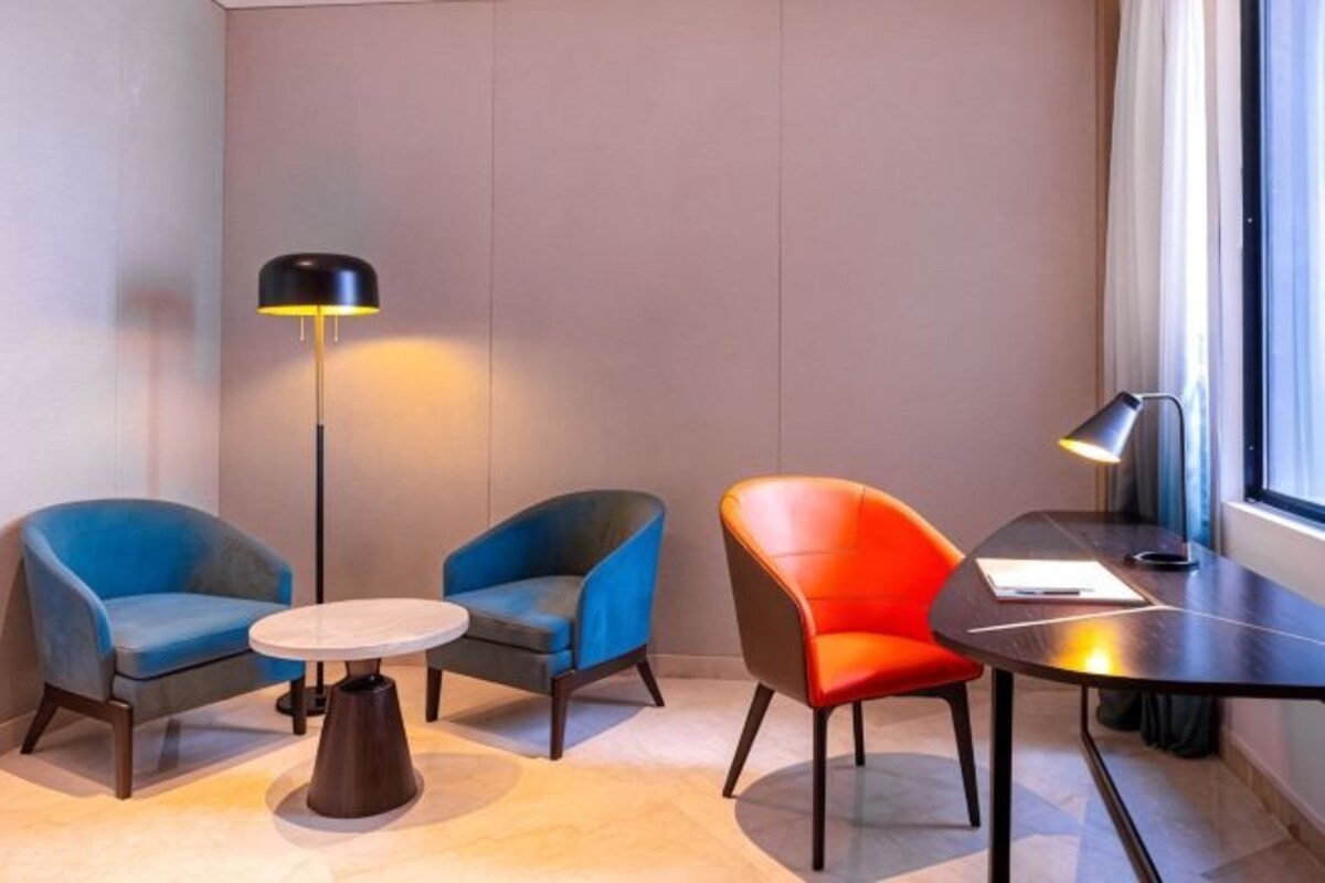 A modern hotel room with two armchairs, a small round table, and a floor lamp.