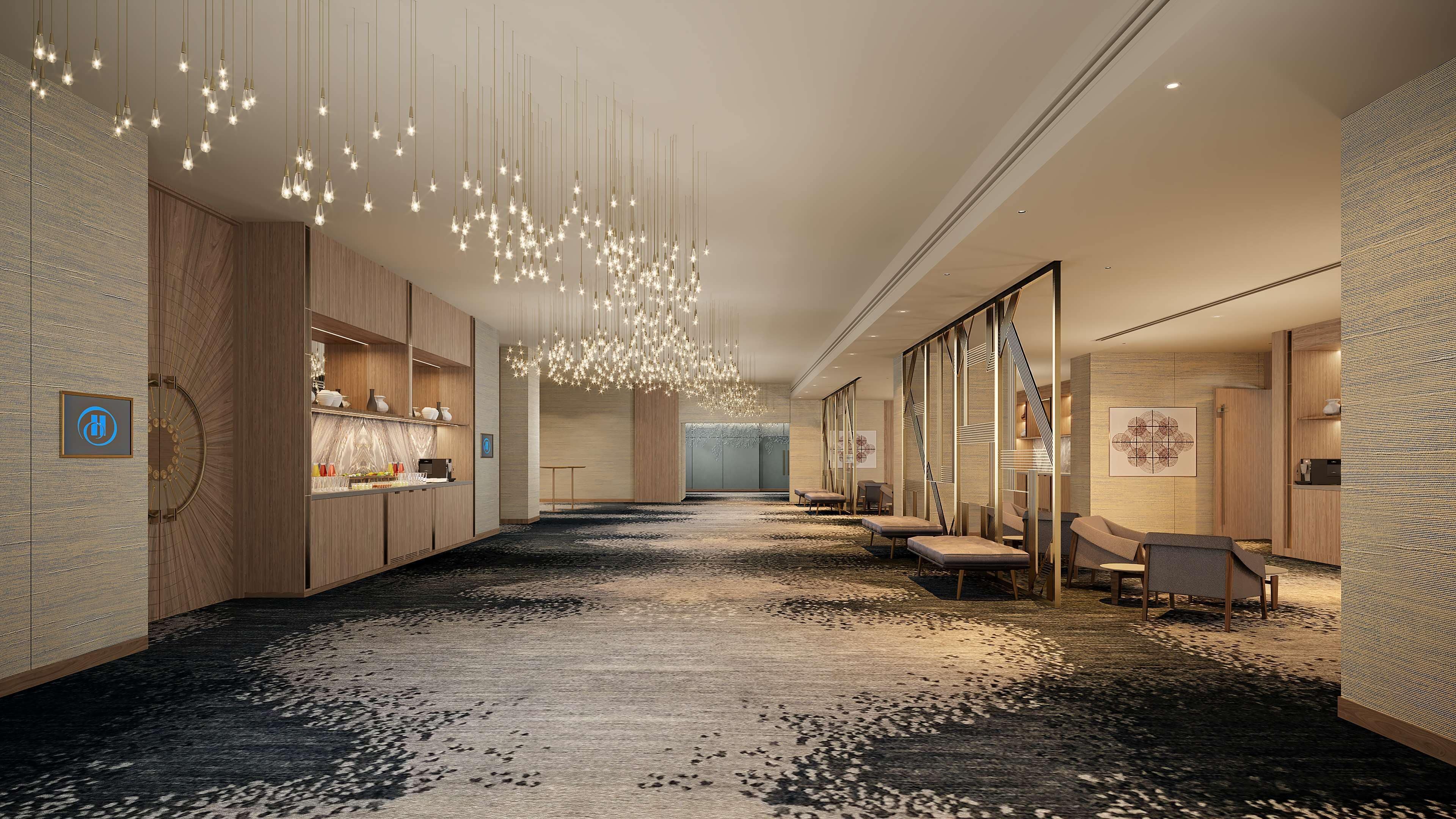 A modern hotel lobby with a long corridor, seating areas, and a reception desk.