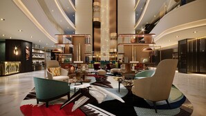 A spacious lobby with modern furnishings, a central column, and a mezzanine level. - Hilton Kinshasa (Kinshasa)