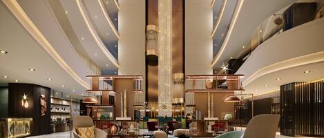 A spacious lobby with modern furnishings, a central column, and a mezzanine level.