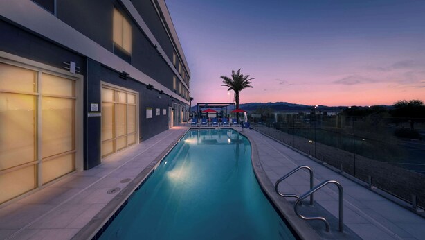 A swimming pool with a view of a modern building and a palm tree. - Home2 Suites Lake Havasu City, Az (Lake Havasu City)