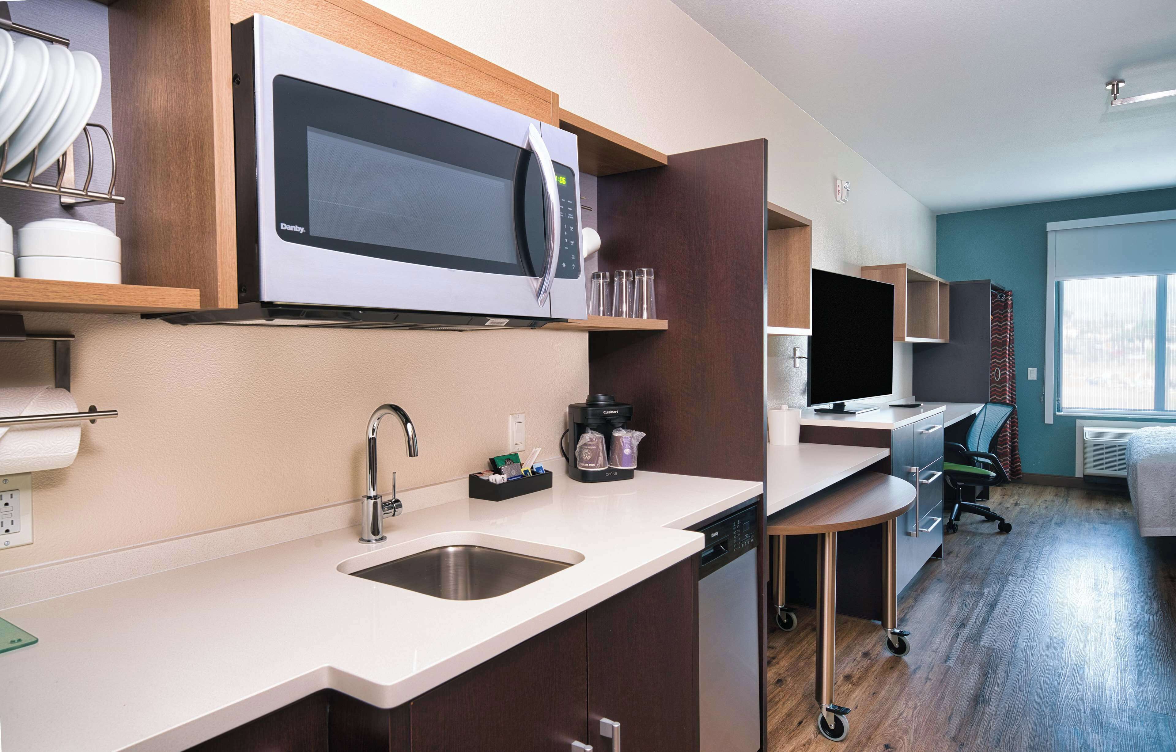 A compact kitchen with a built-in microwave, a sink, and a coffee maker.